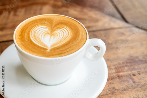 Fotografía Close up white coffee cup with heart shape latte art on wood tab