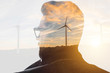 Double exposure portrait of a businessman thinking about renewable electricity combinated with sunset landscape and winmills