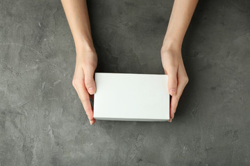 Wall Mural - Female hands with white box on grey textured background