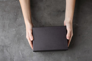 Female hands with black box on grey textured background