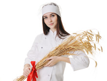 Beautiful Sweet Young Girl In Chef Baker Seller Clothes Holding Ears Of Wheat On A White Background