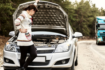 young woman standing near the broken car. The girl opened the hood and look at the engine. Refit woman car