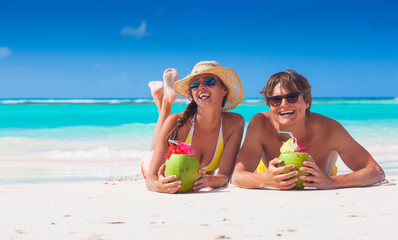 Wall Mural - couple lyind and drinking a coconut cocktail on a tropical beach in Barbados