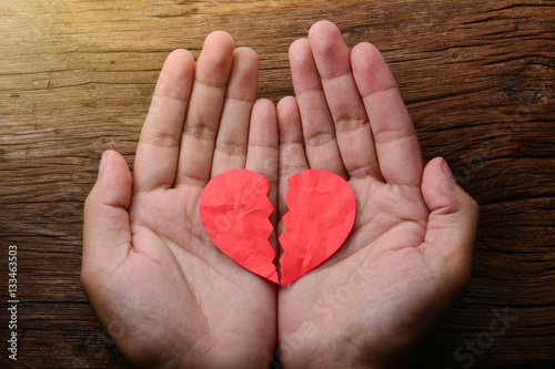 Fotomural man holding a paper broken heart on wooden