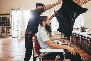 Wall Mural - Barber put a sheet to cover his client from cut hair