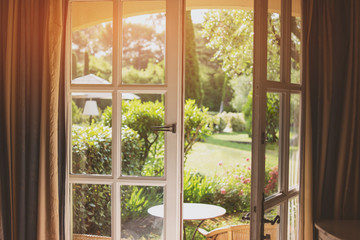 Open door and nature. Green plants and sunlight. House with a garden.