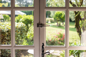 Nature behind door. White frame and dark handle. Look through the glass.