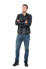 Wall Mural - Young casual man in jeans and leather jacket with crossed arms looking up. Full body length portrait isolated over white background.