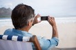 © WavebreakMediaMicro - Rear view of man taking picture on mobile phone at beach