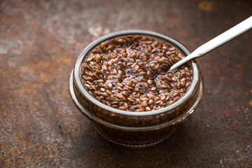 Glass bowl with flax seeds in the water   on the metal background horizontal