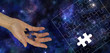 The Missing Piece of the Universe - Female hand holding a piece of jigsaw imprinted with the Universe on a Blue Universe Deep Space background and a jigsaw puzzle outline on right side