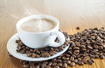 Wall Mural - Cup of coffee in a white cup and coffee beans on wooden table ba