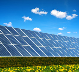 Solar power station on the spring flowering meadow. Photovoltaic panels generate clean energy.