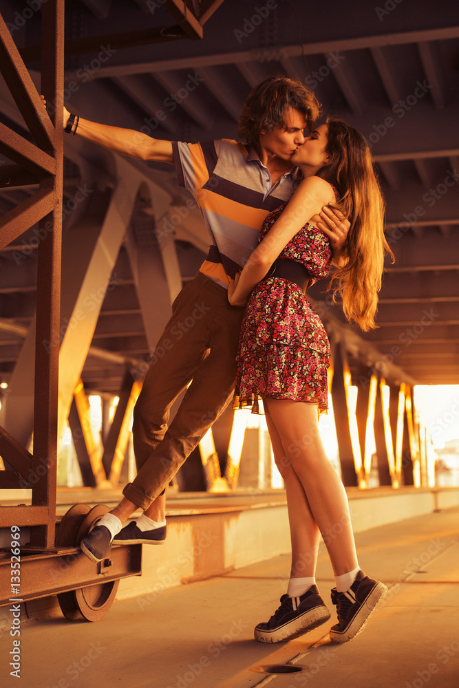 Young couple kissing in the flares of sunset light on a bridge c Stock ...
