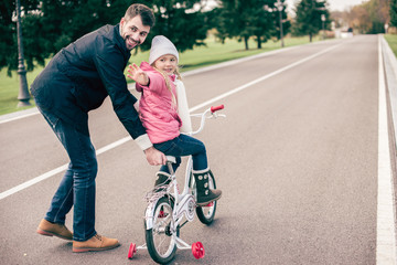 Wall Mural - Father teaching daughter to ride bicycle