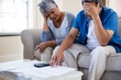 Worried senior couple checking bills in living room