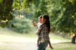 © BalanceFormCreative - Mother holding her daughter and playing around the park on beautiful morning.