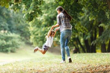 Wall Mural - Mother and daughter playing circling around at the park on beautiful morning.