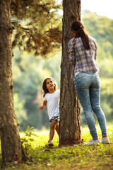 Wall Mural - Mother and daughter play hide and seek at the park. 