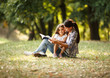 © BalanceFormCreative - Mother and daughter relaxing in park. She's reading a fairy tale to her daughter.
