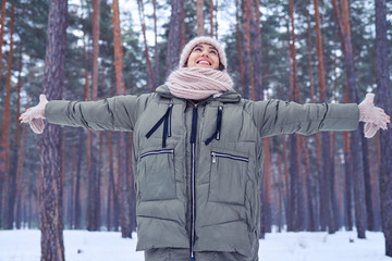 Wall Mural - Woman with spread arms enjoying the beauty of winter forest