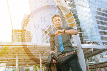 Confident young man holding suit with Briefcase and looking at h