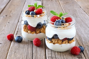 Wall Mural - healthy blueberry and raspberry parfaits in mason jars on a rustic wood background