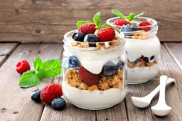 Wall Mural - blueberry and raspberry parfaits in mason jars, still life against a rustic wood background