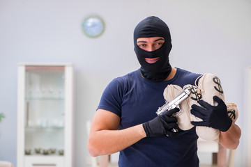 Robber wearing balaclava stealing valuable things