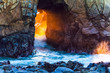 canvas print picture - Waves crash through the Keyhole Arch as light from the setting sun passes through the opening
