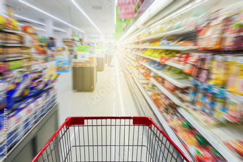 Fotografía Supermarket aisle with empty red shopping cart
