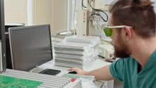 Technician Putting On Protective Eyewear And Testing PCBA With Special Equipment