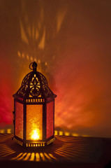 Metal Vintage Lantern background lit by candlelight with deep red and gold colors/Metal Vintage Lantern lit by candle light with brilliant red and gold tones. Patterns of colored light on background