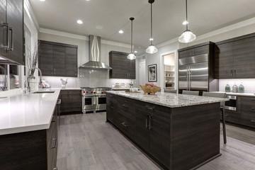 Modern gray kitchen features dark gray flat front cabinets paired with white quartz countertops and a glossy gray linear tile backsplash. Northwest, USA.