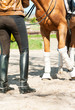 Horse legs in bandages with riding leather horsewoman boots. Out