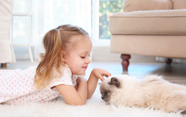 Cute little girl lying on floor with fluffy cat