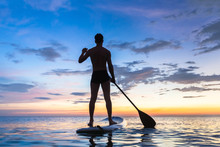 Silhouette Of Stand Up Paddle Boarder Paddling At Sunset, Sea