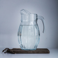 Big water jug full of cold fresh water on wooden desk against wh