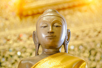 close up face on buddha head statue with Bokeh background and lighting effect.      Selective focus face buddha statue.