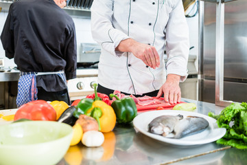 Chef putting salt on fish while cooking in kitchen