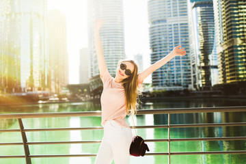 Happy woman raises her hands up standing on the bridge before sk