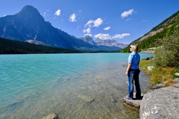 Canvas Print - Woman looking at the beautiful view of clear turquoise lake and rocky mountains. Waterfowl lake. Canadian Rockies. Banff National Park. British Columbia. Canada.