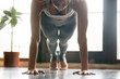© fizkes - Young attractive woman practicing yoga, standing in Push ups, press ups, phalankasana exercise, Plank pose, working out, wearing sportswear, grey pants, bra, indoor, home interior background. Close up