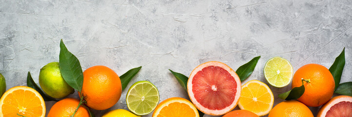 Citrus fruit on grey concrete table. Food background. Healthy eating. Long banner format good for web.