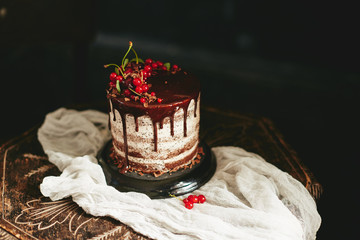 Wall Mural - Chocolate cake with red berries currant on old wooden table