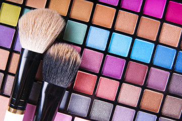 make-up brushes on colorful eye shadows palette