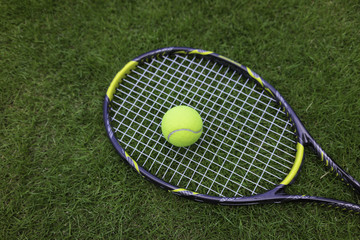 Wall Mural - Tennis ball and racket on green grass background