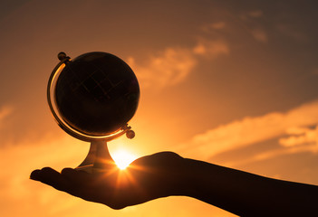 silhouette of hand holding globe.