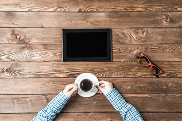 Top view of student sitting at wooden table and hold a cup of co