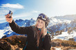woman in the mountains winter holidays dress in a ski suite take photo on the action camera